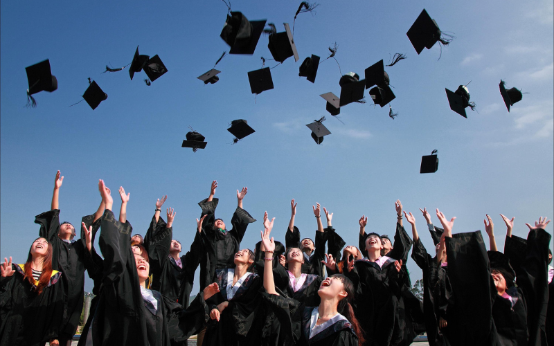 college graduates throwing caps in the air